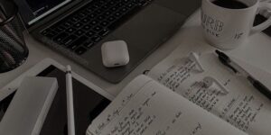 Работно бюро с лаптоп, отворени бележници и кафе, илюстриращо процеса на създаване на съдържание и планиране.